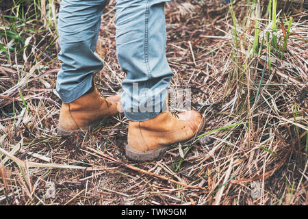 - Nahaufnahme Bergsteiger aus braunem Leder Stiefel stehen auf trocken ist, feuchten Wiese im Regenwald Stockfoto