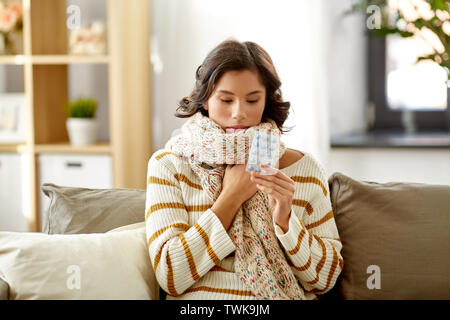 Kranke Frau in Schal mit Medizin Pillen zu Hause Stockfoto