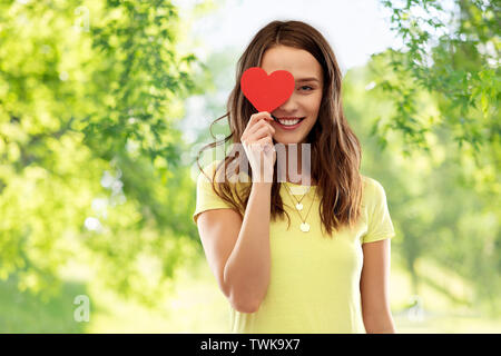 Lächelnd Teenager, die Ihr Auge durch rote Herzen Stockfoto