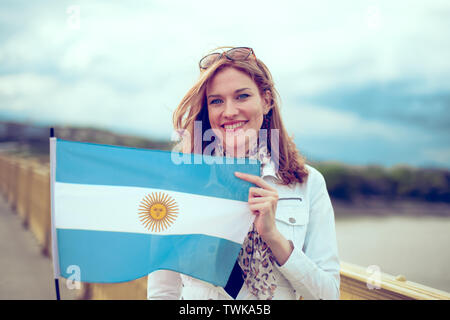 Glückliche junge elegante Frau mit Flagge Argentinien auf der Brücke Stockfoto