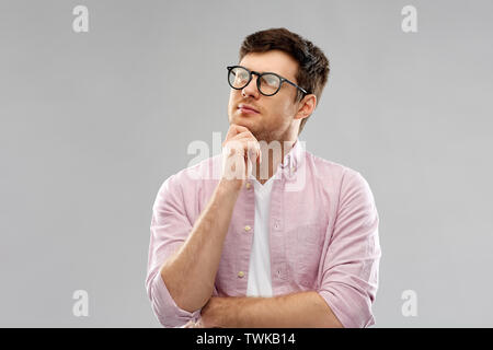Denken junger Mann in Gläser über grauer Hintergrund Stockfoto
