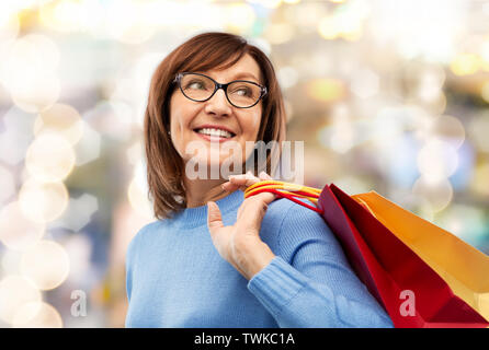 Ältere Frau mit Einkaufstüten über Grau Stockfoto