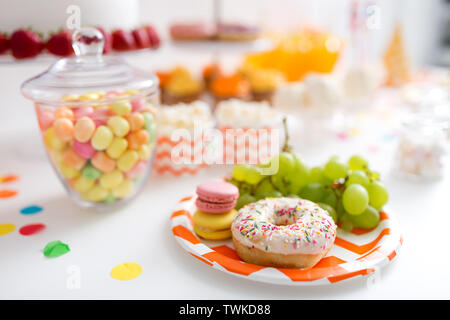 Trauben, Macarons und Krapfen auf Party Tabelle Stockfoto