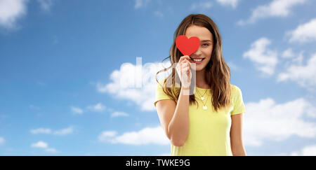 Lächelnd Teenager, die Ihr Auge durch rote Herzen Stockfoto