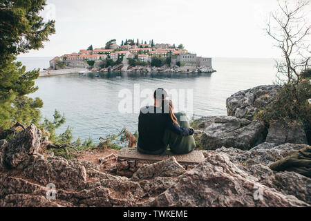 Ein junges Paar von Touristen bewundert die schöne Aussicht auf das Meer und die Insel Sveti Stefan in Montenegro. Stockfoto