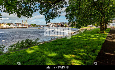 Schöne Sicht zwischen den Zweigen der Bäume auf dem Shannon Fluss mit der Stadt Athlone im Hintergrund, wunderbar sonnigen Tag Stockfoto