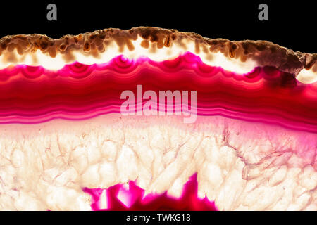 Red orange agate slice striped mineral isolated on black, abstract background Stockfoto