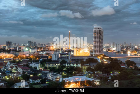 Stadtbild von Rama 8 Brücke über den Fluss Chaophraya mit Gebäuden in der Dämmerung in Bangkok, Thailand glühende Stockfoto