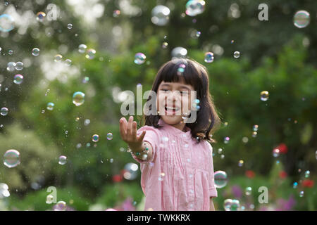 Mädchen versuchen, schwimmende Luftblasen halten Stockfoto