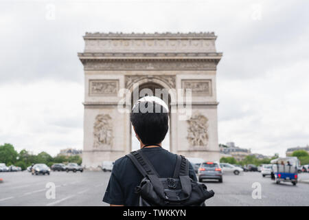 Ein Mann mit Rucksack, Arc de Triomphe, Wahrzeichen und Reiseziel in Paris, Frankreich. Unterwegs in Europa im Sommer Stockfoto