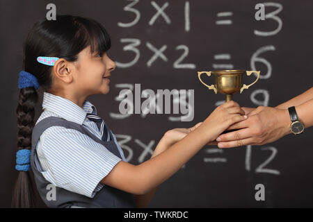 Lehrer geben eine Trophäe mit einer Mädchen Stockfoto