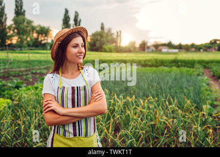 Junge Frau Bauer auf Gemüse auf Küche suchen - Garten in der Landschaft. Agrar- und Landwirtschaft Konzept. Organic Farm Stockfoto