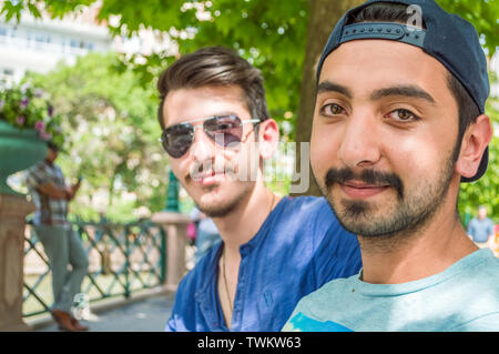 Close up Portraits von zwei glückliche junge Freunde sitzen unter dem Baum im Stadtzentrum. Stockfoto