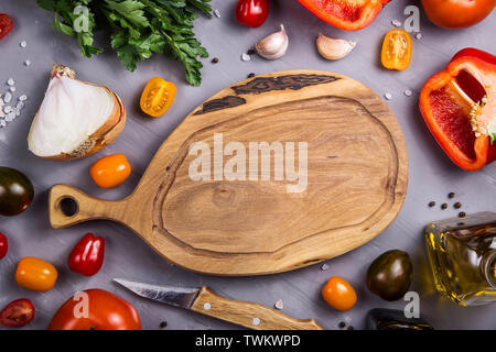 Leere Holz Schneidebrett mit Platz für Text unter den Zutaten zum Kochen Gemüse mit Tomaten, Pfeffer, Knoblauch. Ansicht von oben, flach, cop Stockfoto