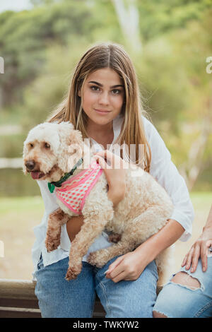 Ein junges Mädchen sitzt mit ihrem adorable Puppy auf ihrem Schoß im Freien. Stockfoto