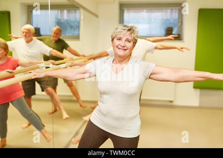 Vital senior macht Reha Physiotherapie auf dem Ballett bar in der Physiotherapie Stockfoto