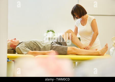 Senior als Patient in der Reha erhält Physiotherapie auf das Kniegelenk für Schmerzlinderung Stockfoto