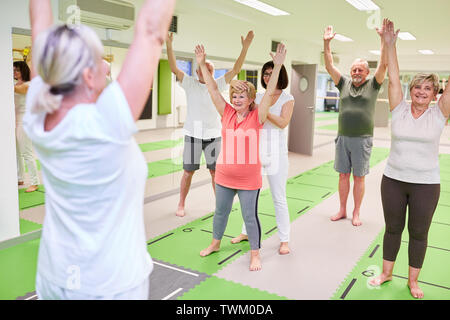 Gruppe von Senioren tun Zurück Übungen in der Physiotherapie unter der Leitung der Rehabilitation Trainer Stockfoto