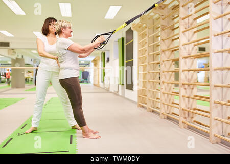 Fitness Trainer oder Physiotherapeuten gibt Senior in sling Training Stockfoto