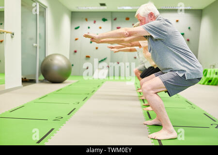 Senior Group Fitness Klasse trainiert Kraft- und Beinmuskulatur mit Kniebeugen Stockfoto