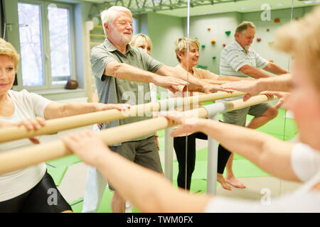 Gruppe von Senioren für Rehabilitation Physiotherapie auf einem Ballett bar vor dem Spiegel Stockfoto