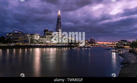 Dämmerung in London, wie die Sonne hinter einem bewölkten Himmel über der Themse. Stockfoto