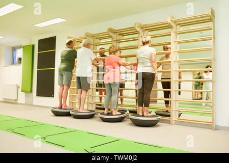 Gruppe von Senioren übung Fitness und Balance auf der Bosu Ball an der Wand bars Stockfoto