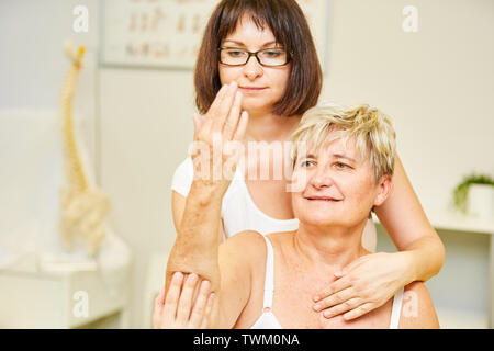 Heilpraktiker wird zur Behandlung von Schmerzen im Ellenbogen eines Patienten mit Physiotherapie Stockfoto