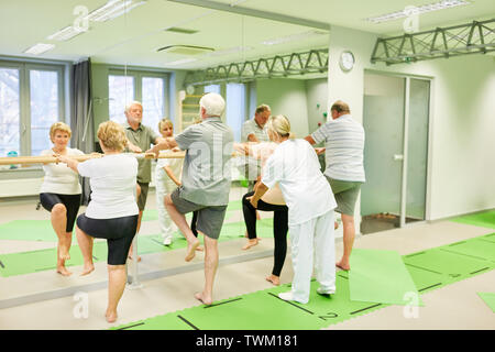 Therapeut kümmert sich um die Senioren in Physiotherapie an der Ballett bar als Absturzsicherung Stockfoto