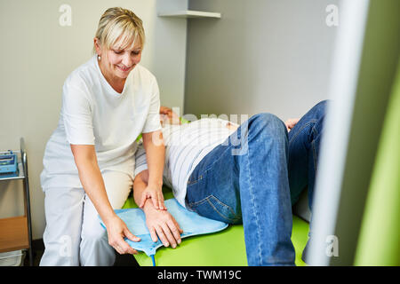 Heilpraktiker behandelt Patienten mit Rückenschmerzen in der Lendenwirbelsäule mit Magnetfeldtherapie Stockfoto