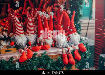 Bunte rote Spielzeug Zwerge Zwerge in Red Caps Hüte sitzen auf Zähler an traditionellen Urlaub Weihnachtsmarkt im Freien. Beliebte Attraktion Stockfoto