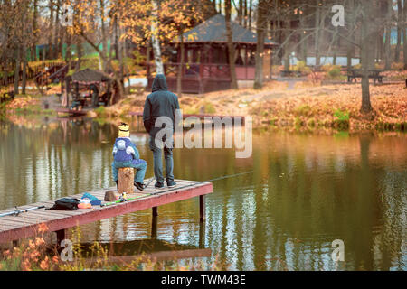 Erwachsener und Kind auf einer hölzernen Pier, Angeln Brücke. Herbst Park. Laub, sonnigen Tag, natürliche Hintergrund. Stockfoto