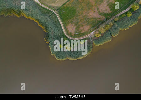 Von oben nach unten Blick auf den See, Ufer mit der Straße und Feld. Stockfoto