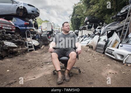 Auto breakers yard Geschäftsinhaber sitzt stolz in seinem Bürostuhl im Hof Stockfoto