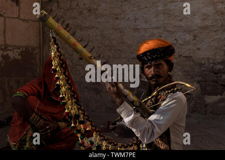 Ein Rajasthani Geiger Volksmusik außerhalb Mehrangarh Fort, Jodhpur, Indien, während seine Frau unter einem Schleier saß. Stockfoto