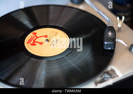 Nahaufnahme eines klassischen jazzigen Pablo Musical-Plattenalbums, das auf einem Plattenspieler, Tonarm und Kopfschale spielt. Leichte Bewegungsunschärfe auf dem Vinyl selbst. Stockfoto