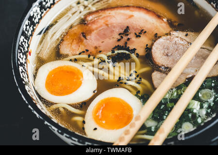 Ramen Suppe mit Udon Nudeln, Schweinefleisch und Eier auf dunklem Hintergrund Stockfoto