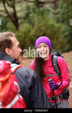 Paar Spaß lachen Wandern im Wald. Multikulturelle Frau und Mann Wanderer auf Wanderung in den Wäldern tragen Rucksäcke draussen in der Natur. Stockfoto