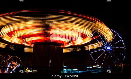 Spinning fahren und Riesenrad bei Nacht Messe mit Bewegungsunschärfe Stockfoto