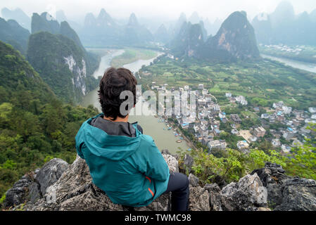 Mann über den Li Fluss und die Karstlandschaft auf einem Hügel in Xingping, Guangxi Provinz, China Stockfoto