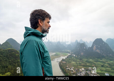 Mann über den Li Fluss und die Karstlandschaft auf einem Hügel in Xingping, Guangxi Provinz, China Stockfoto