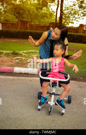 Glückliche Mutter spielen Sie mit Ihrem Kind, während er einen Kinderwagen im Park High resolution Image Gallery. Stockfoto