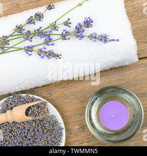Lavendelblüten, aromatische Kerzen, und Handtücher auf Holz- Hintergrund Stockfoto