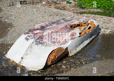 Invertiert Boot liegt am Ufer des beschädigten Rumpf aufgegeben. Stockfoto