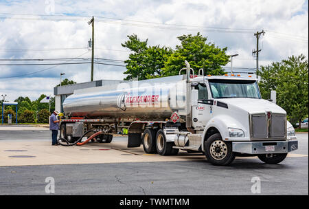 MOORESVILLE, NC, USA - 19. JUNI 2019: Alexander & Sohn Tankwagen, füllen eine Tankstelle Tank, während Treiber steht durch die, in der Smart Phone. Stockfoto