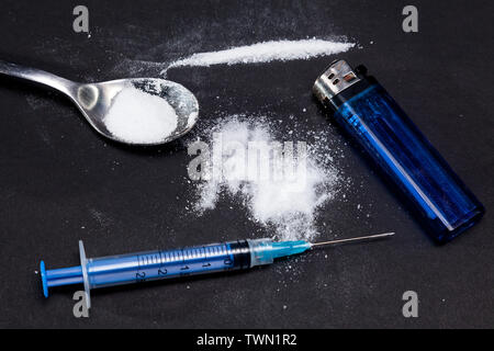 Kokain Pulver in einem Löffel und eine Spritze mit Drogen auf einem schwarzen Hintergrund. Pfad des Kokains Stockfoto