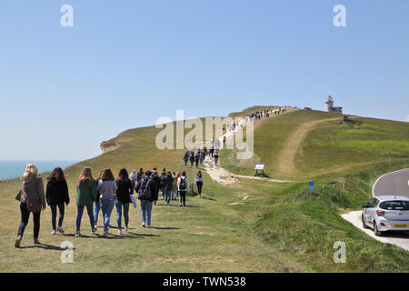 Studenten beim Spaziergang zum Leuchtturm Belle Tout in den South Downs in Beachy Head, East Sussex, Großbritannien, ist ein Abschnitt des Felswegs nun im Meer gefallen Stockfoto