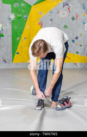 Kletterer setzt auf felsigen Schuhe in einer Bouldern Halle in einer Kletterhalle Stockfoto