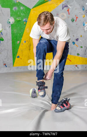 Kletterer setzt auf felsigen Schuhe in einer Bouldern Halle in einer Kletterhalle Stockfoto