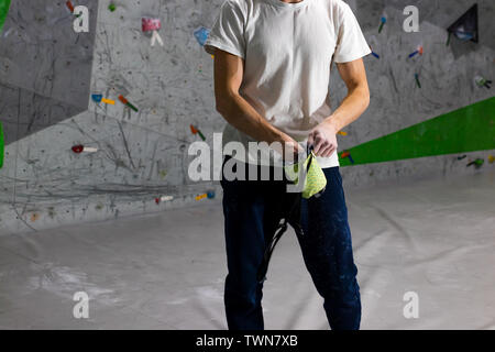 Kletterer Mann schob seine Hände in eine Tasche von Magnesia Pulver hinter seinem Rücken in der Boulder Halle Stockfoto